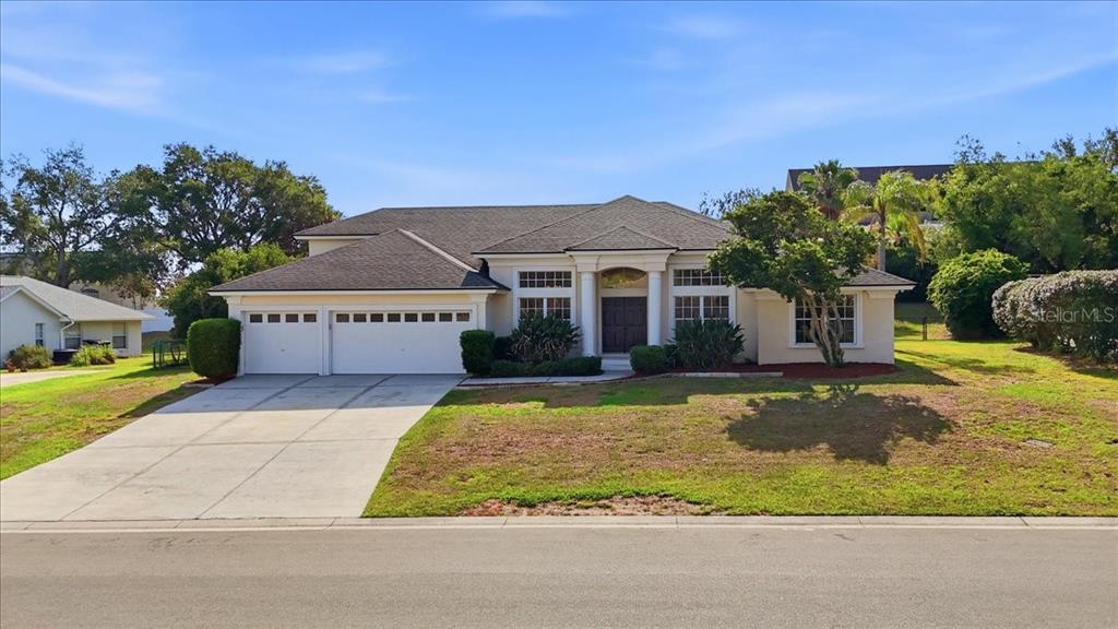 An aerial view shows a single-story house with a gray roof and a concrete driveway — 5628 WOODWIND HILLS DRIVE, LAKELAND, FL