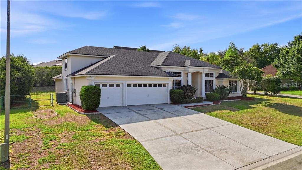 A single-story suburban house with a three-car garage and a paved driveway — 5628 WOODWIND HILLS DRIVE, LAKELAND, FL