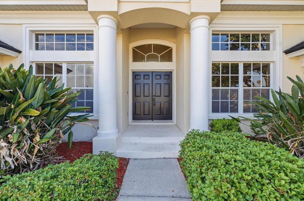 A bright living room features a beige sofa, two armchairs, and a coffee table — 5628 WOODWIND HILLS DRIVE, LAKELAND, FL