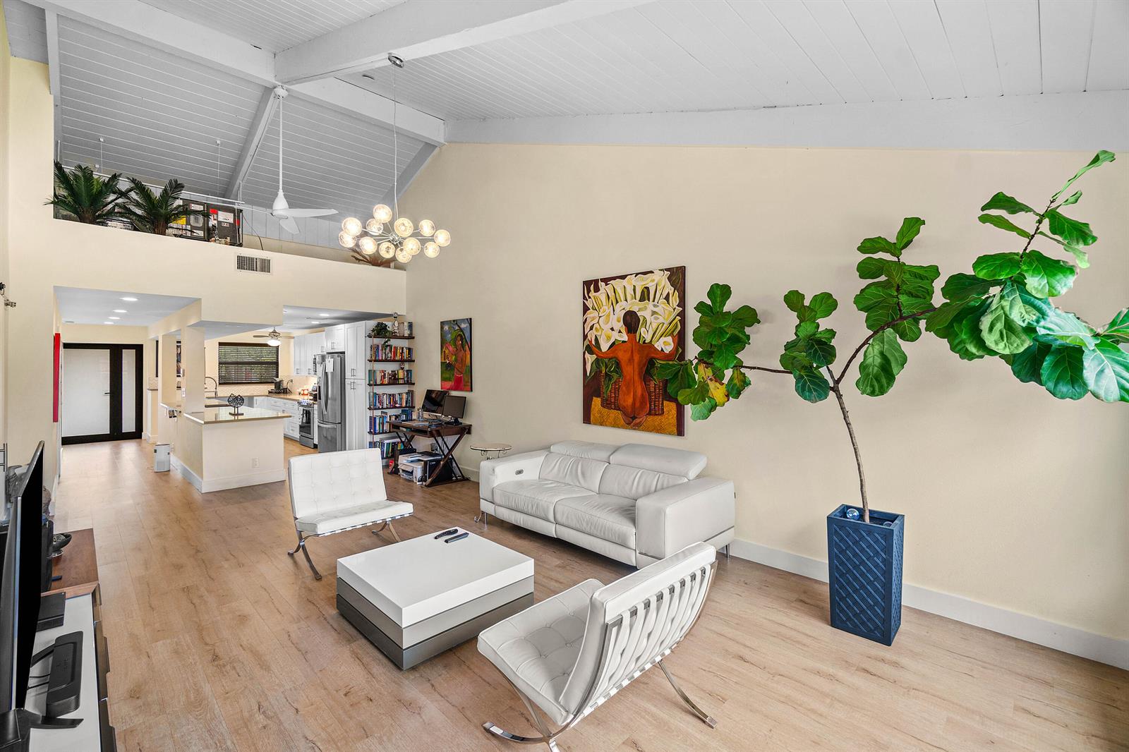 A bright living room with vaulted ceilings, white leather furniture, and a large potted plant — 830 Greensward Court # h, Delray Beach FL 33445, DELRAY BEACH, FL