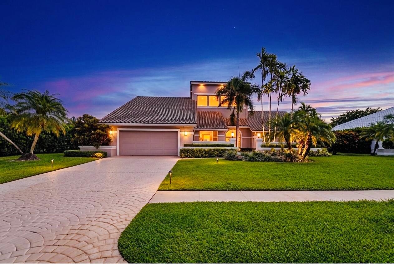A two-story suburban house with a paved driveway, manicured lawn, and palm trees at dusk — 4961 Bocaire Boulevard, Boca Raton FL 33487, BOCA RATON, FL