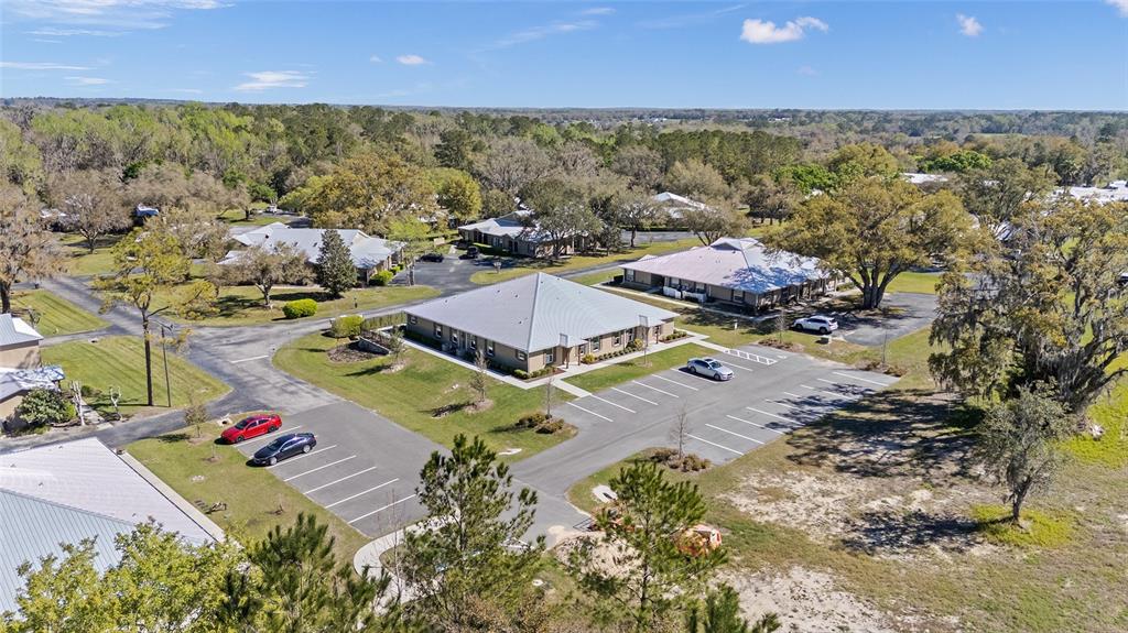 An aerial view shows several single-story buildings surrounded by parking lots and wooded areas — 7462 NW 44TH LANE, OCALA, FL