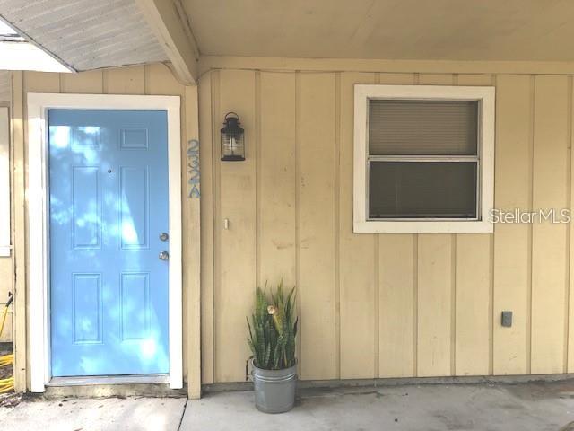 A light blue front door sits next to a window on a tan exterior wall — 232 BAMBOO DRIVE UNIT A, PORT CHARLOTTE, FL