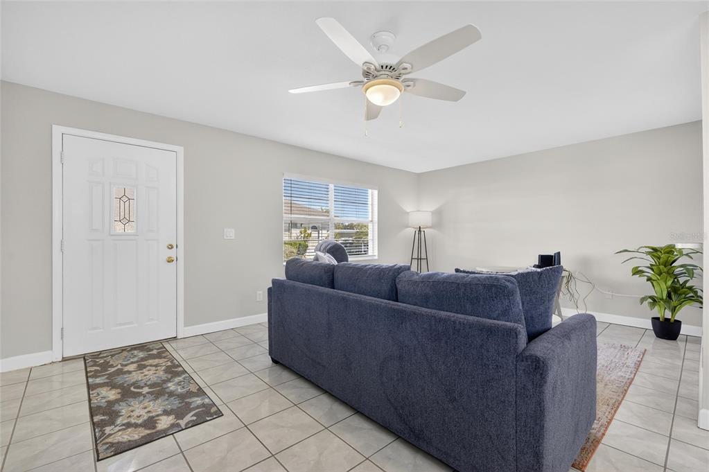 A living room with light gray walls, white tile floors, a blue sofa, and ceiling fan — 301 ANDOVER PLACE S UNIT 171, SUN CITY CENTER, FL