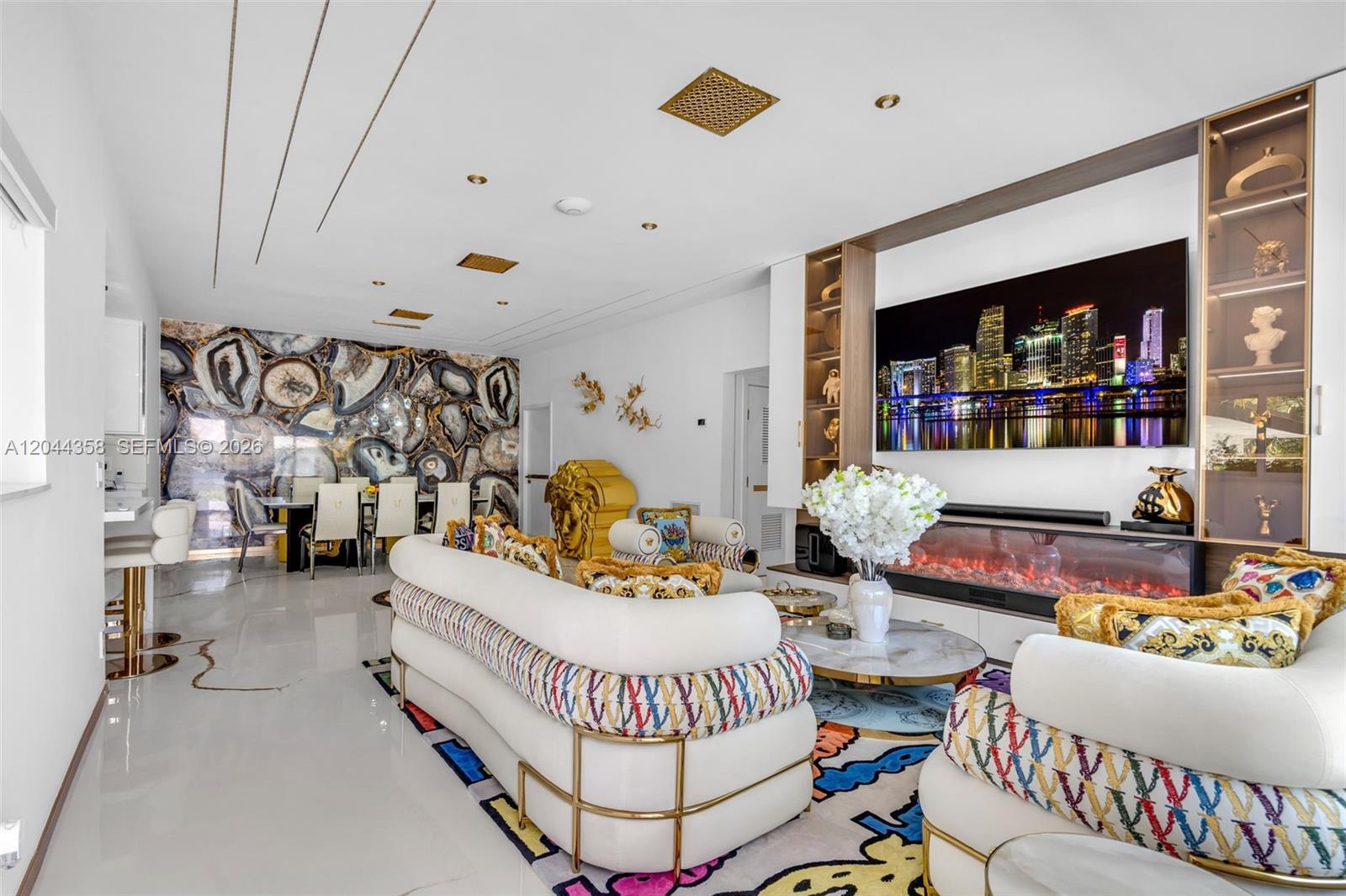 A living room features white curved sofas, a large television, and a decorative stone wall — BISCAYNE PARK, FL