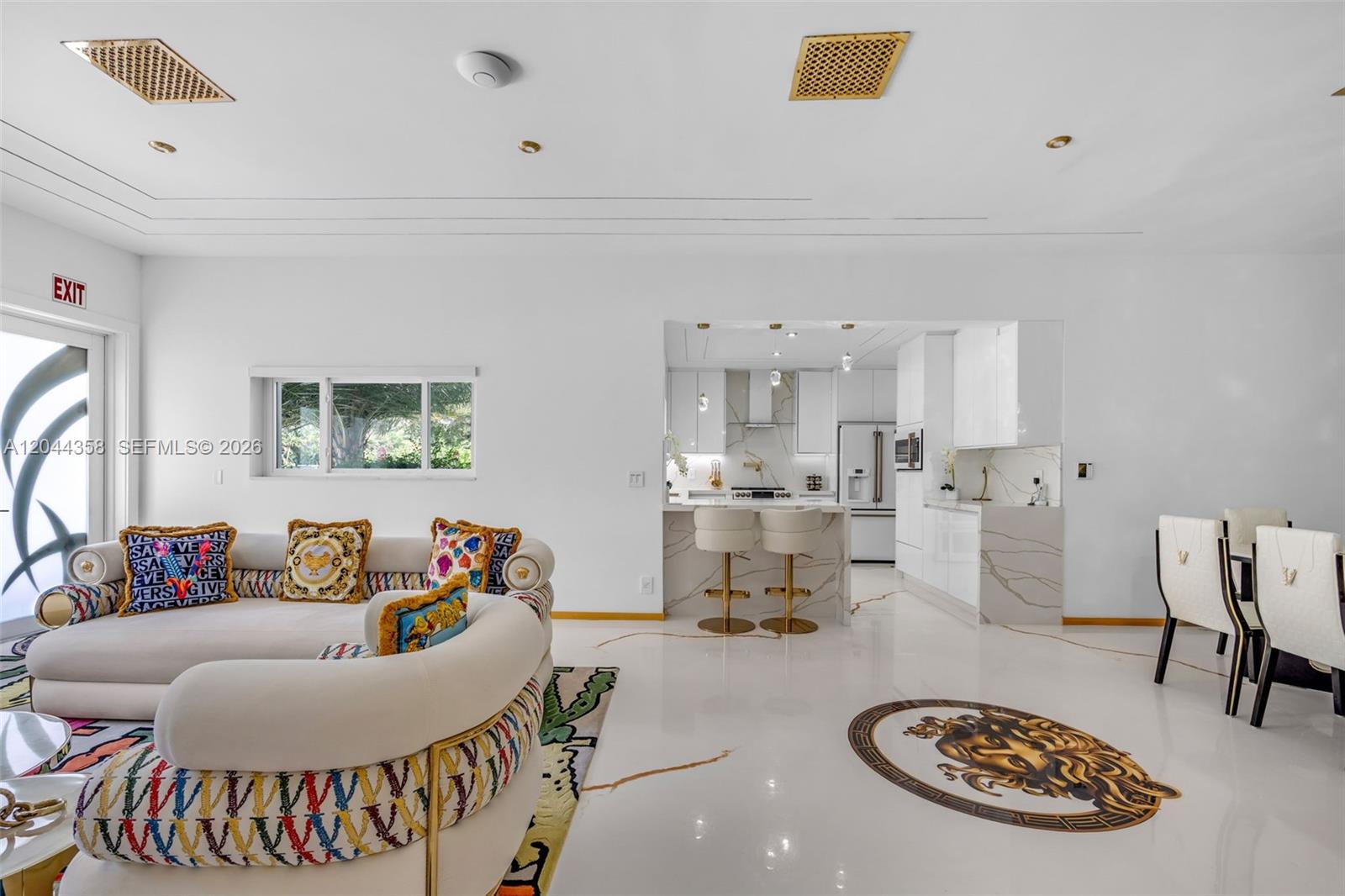 A modern open-concept living room and kitchen featuring white marble floors and gold accents — BISCAYNE PARK, FL