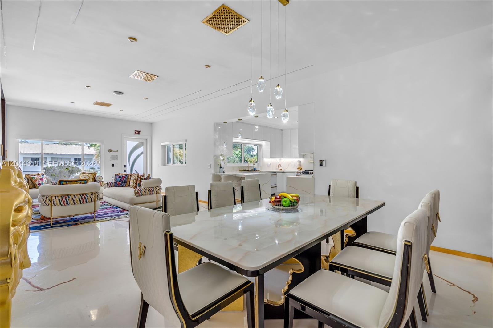 A dining area with a marble-topped table and chairs opens into a living room — BISCAYNE PARK, FL