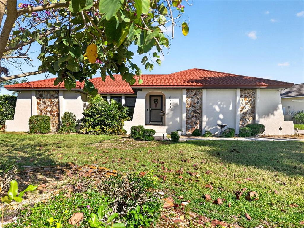 A single-story house with a red tile roof, stone accents, and a front lawn — 5019 SAN MASSIMO DRIVE, PUNTA GORDA, FL