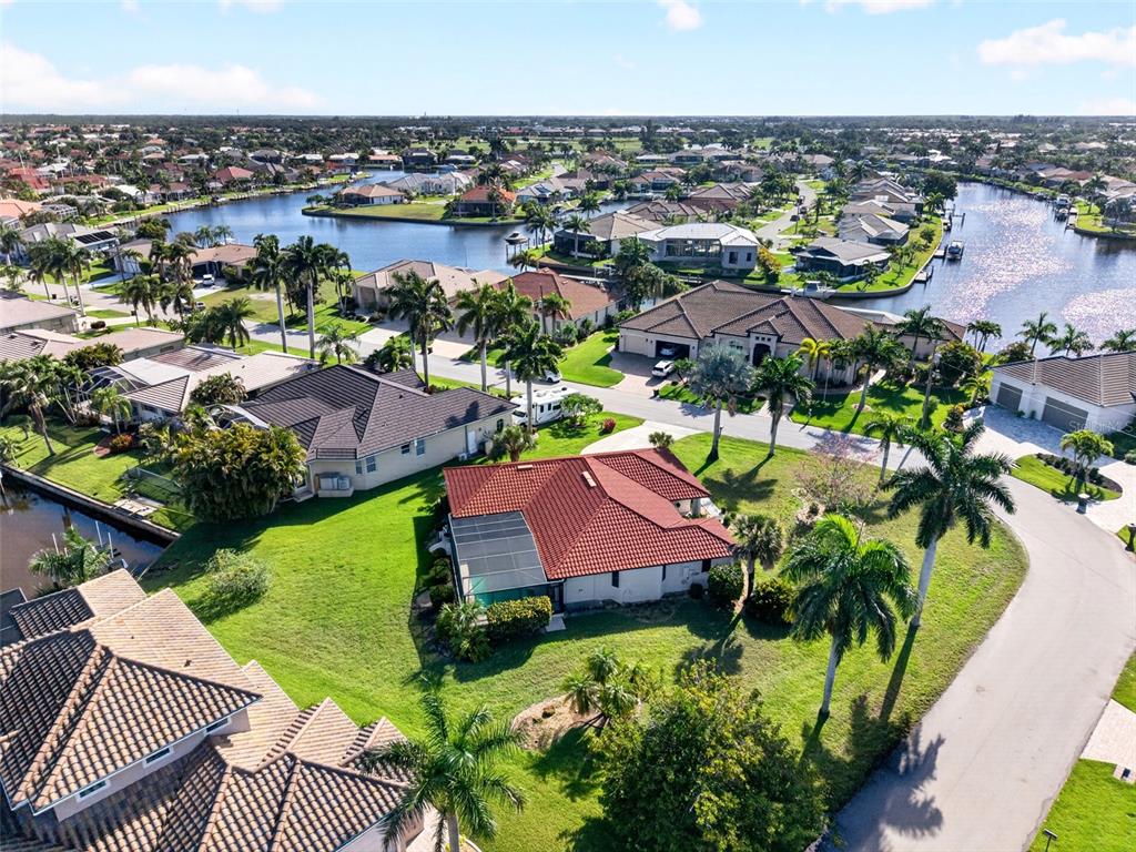 An aerial view of a residential neighborhood featuring houses with tiled roofs and palm trees — 5019 SAN MASSIMO DRIVE, PUNTA GORDA, FL