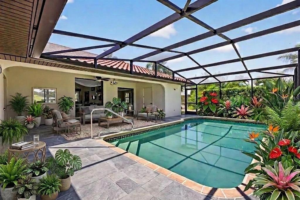 A screened-in patio features a swimming pool, tiled flooring, and various potted tropical plants — 5019 SAN MASSIMO DRIVE, PUNTA GORDA, FL