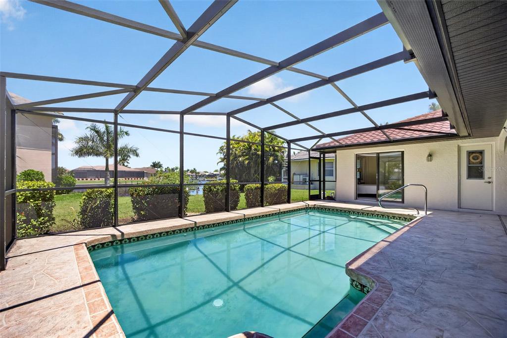 A screened-in patio features a rectangular swimming pool with a concrete deck and landscaping — 5019 SAN MASSIMO DRIVE, PUNTA GORDA, FL