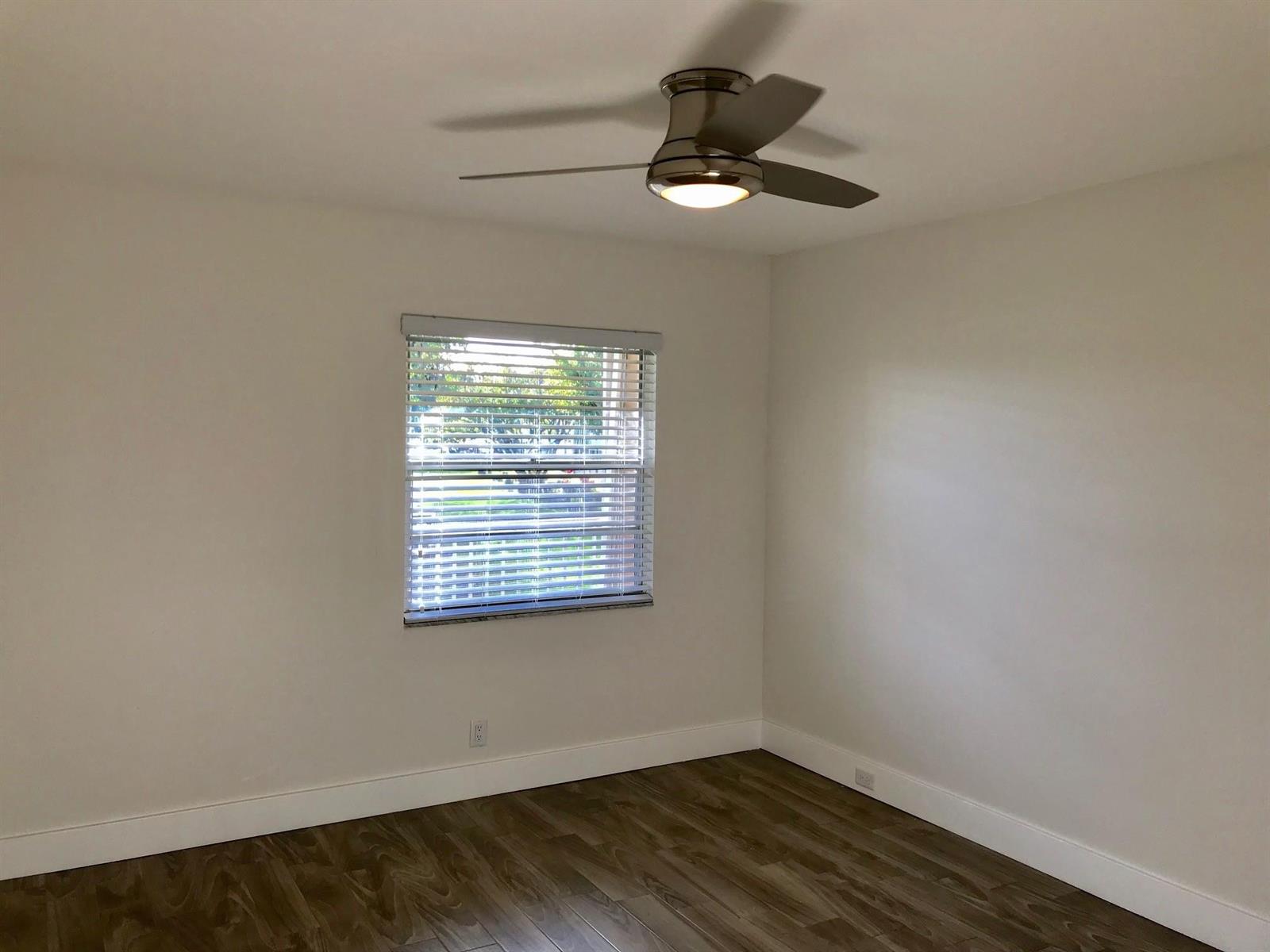 An empty bedroom features white walls, wood-look flooring, a ceiling fan, and a single window — 300 SW 134th Way # E210, Hollywood FL 33027, HOLLYWOOD, FL