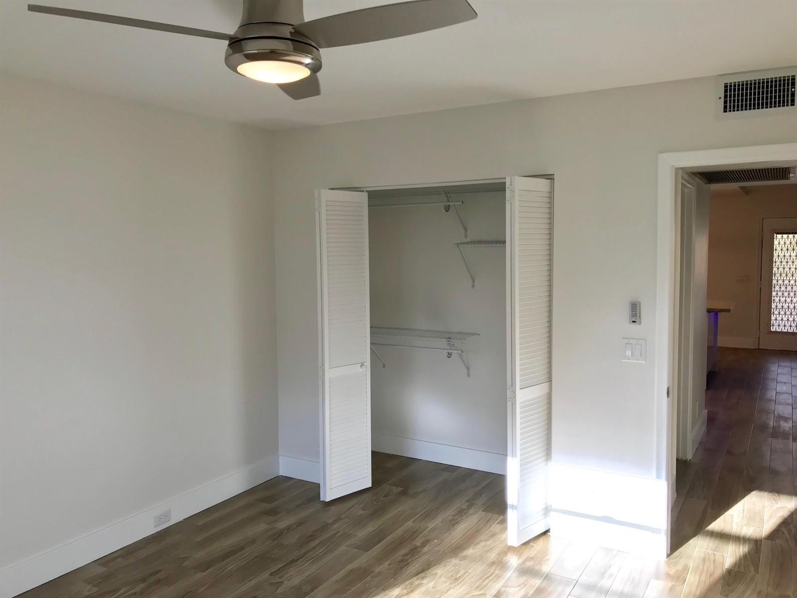 A bedroom with light gray walls, wood-look flooring, a ceiling fan, and an open closet — 300 SW 134th Way # E210, Hollywood FL 33027, HOLLYWOOD, FL