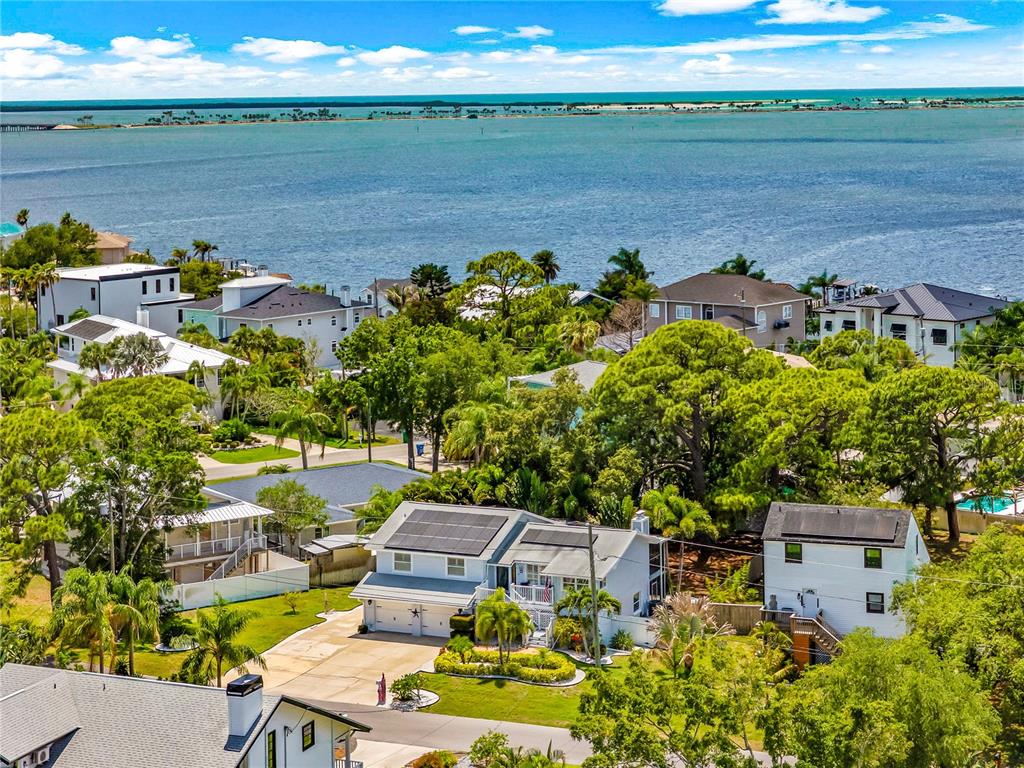 An aerial view shows a residential neighborhood with houses, lush trees, and a waterfront — 201 LAGOON DRIVE, PALM HARBOR, FL