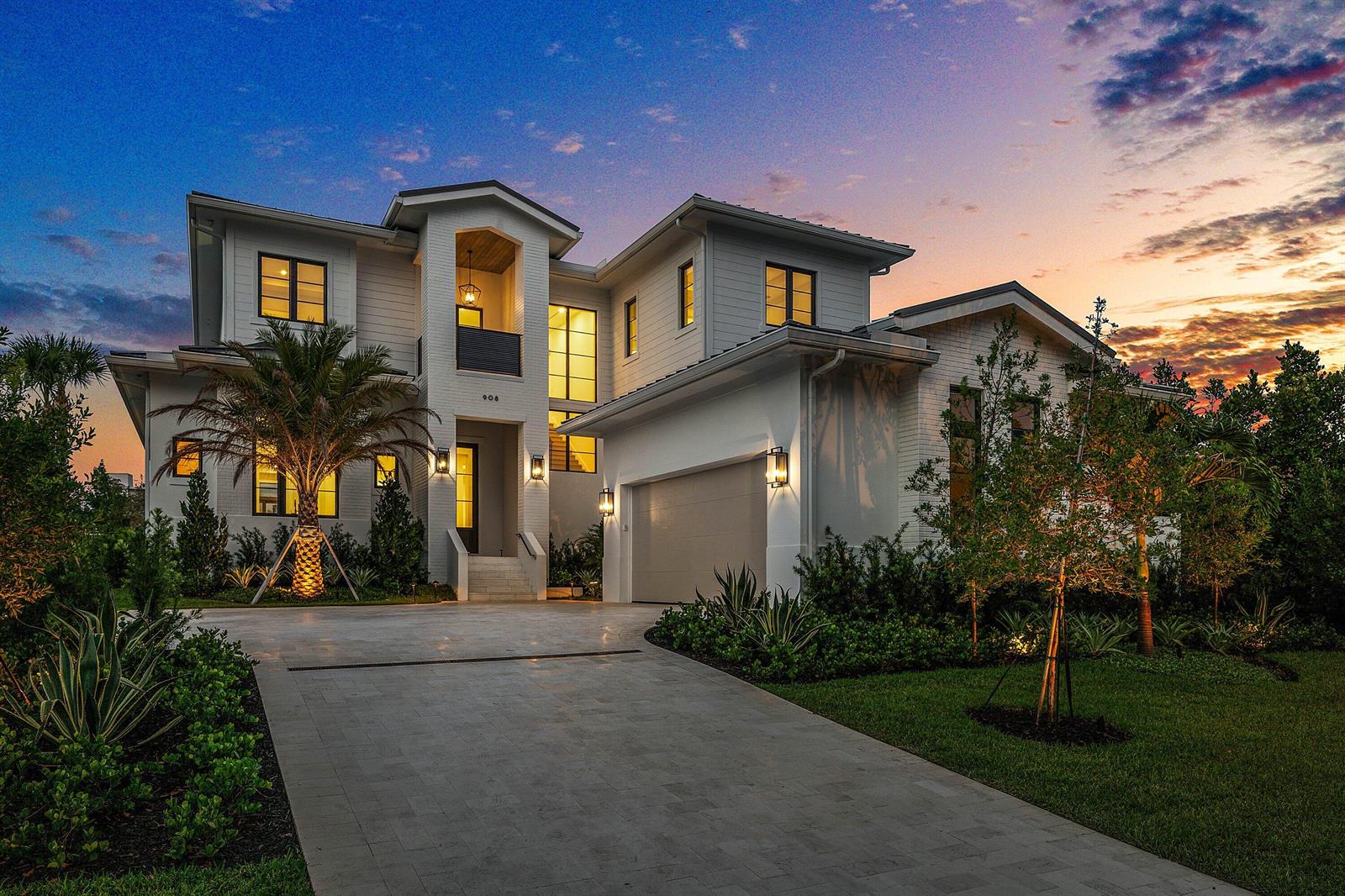 A two-story white house with a paved driveway, palm tree, and attached garage at sunset — 908 N Atlantic Drive, Lantana FL 33462, LANTANA, FL