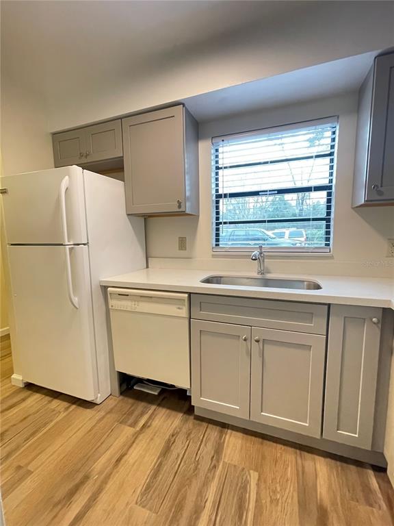 A kitchen features gray cabinets, a white refrigerator, a dishwasher, and a window above the sink — 914 SW 59TH TERRACE UNIT A, GAINESVILLE, FL