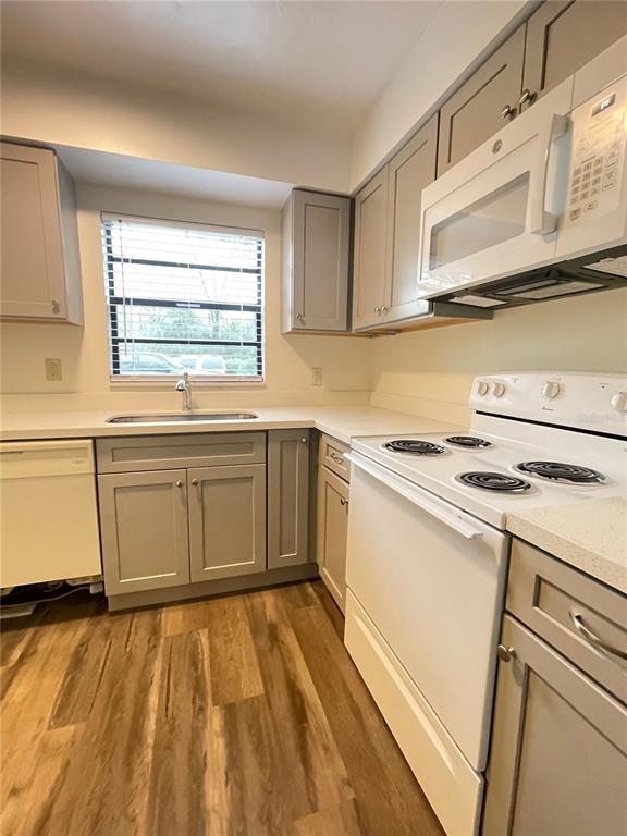 A kitchen features light gray cabinets, white appliances, a window above the sink, and wood-look flooring — 914 SW 59TH TERRACE UNIT A, GAINESVILLE, FL