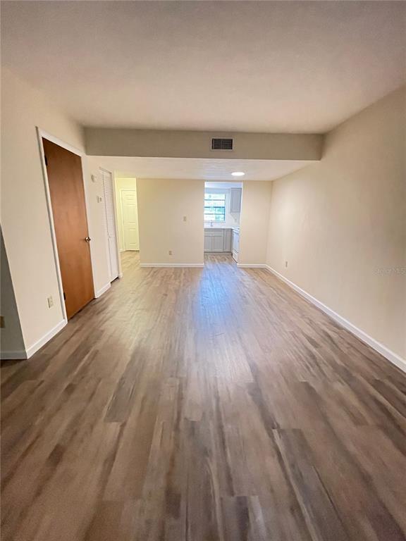 A long, open-concept room features light wood-look flooring and leads into a kitchen area — 914 SW 59TH TERRACE UNIT A, GAINESVILLE, FL