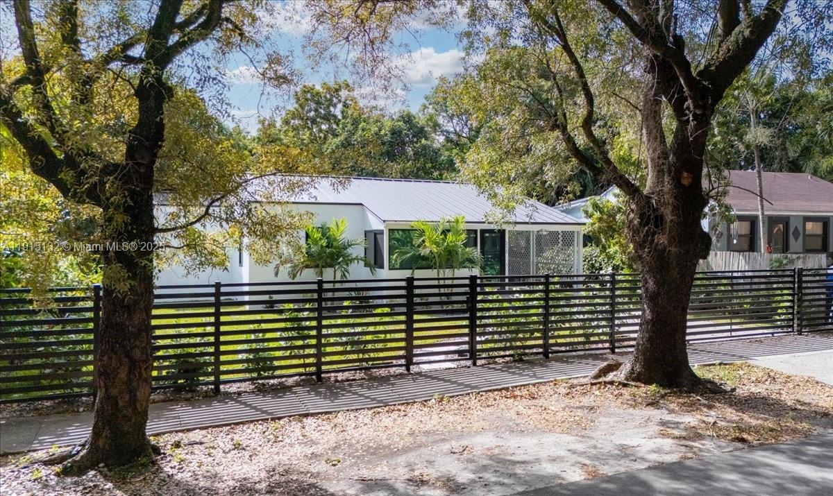 A white house with a metal roof sits behind a black horizontal slat fence — 5220 SW 6 ST, Miami FL 33134, MIAMI, FL