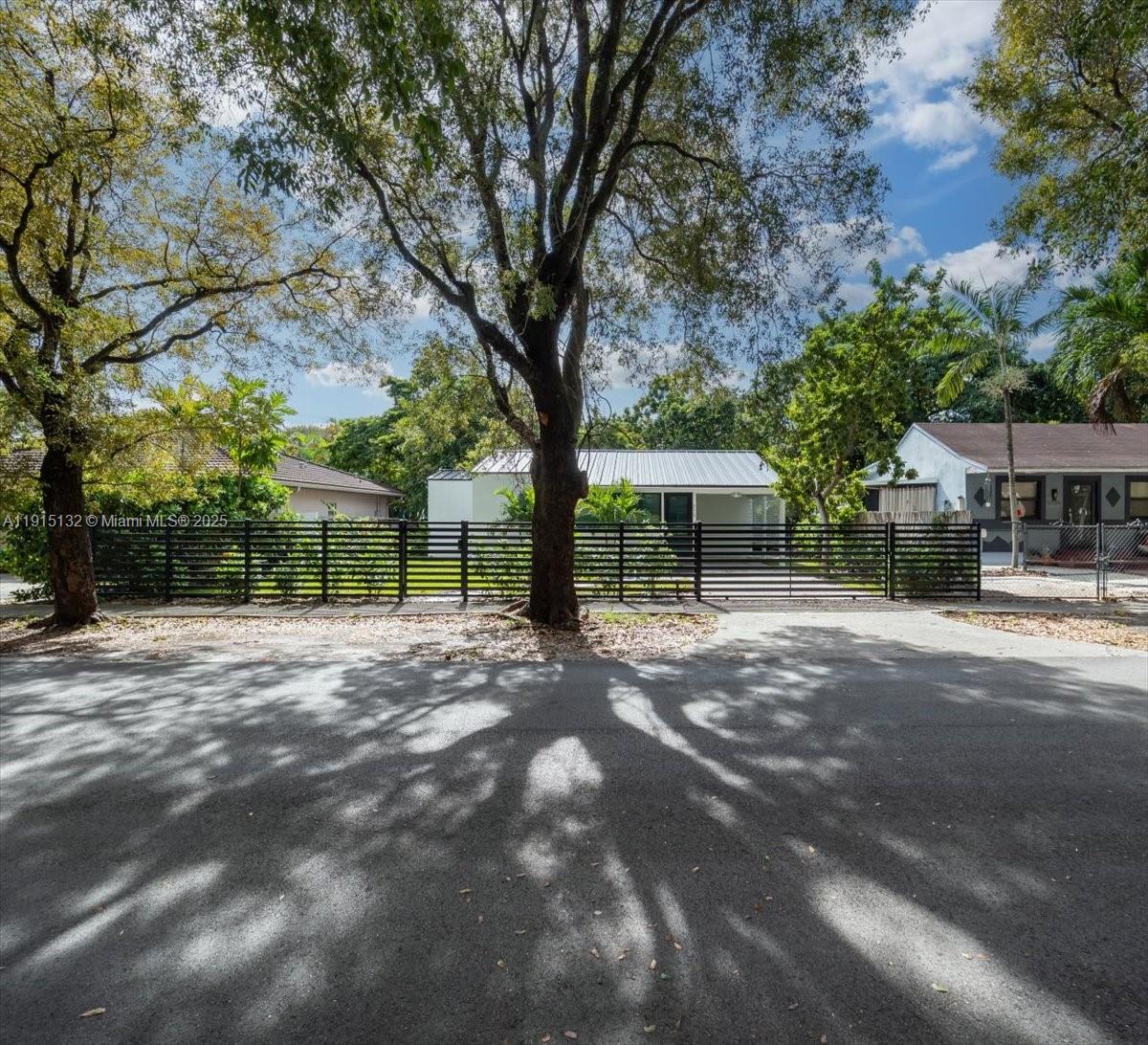 A single-story house with a metal roof is visible behind a black horizontal slat fence — 5220 SW 6 ST, Miami FL 33134, MIAMI, FL