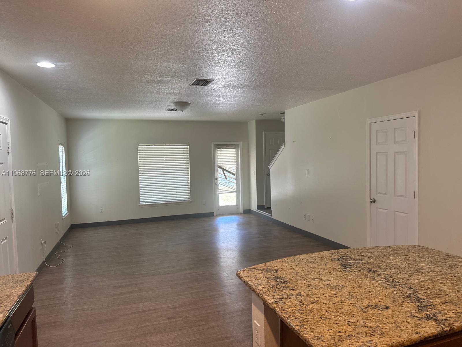 An open-concept living area features wood-look flooring, light-colored walls, and a granite-topped kitchen island — 4717 Chatterton Way, Riverview FL 33578, RIVERVIEW, FL