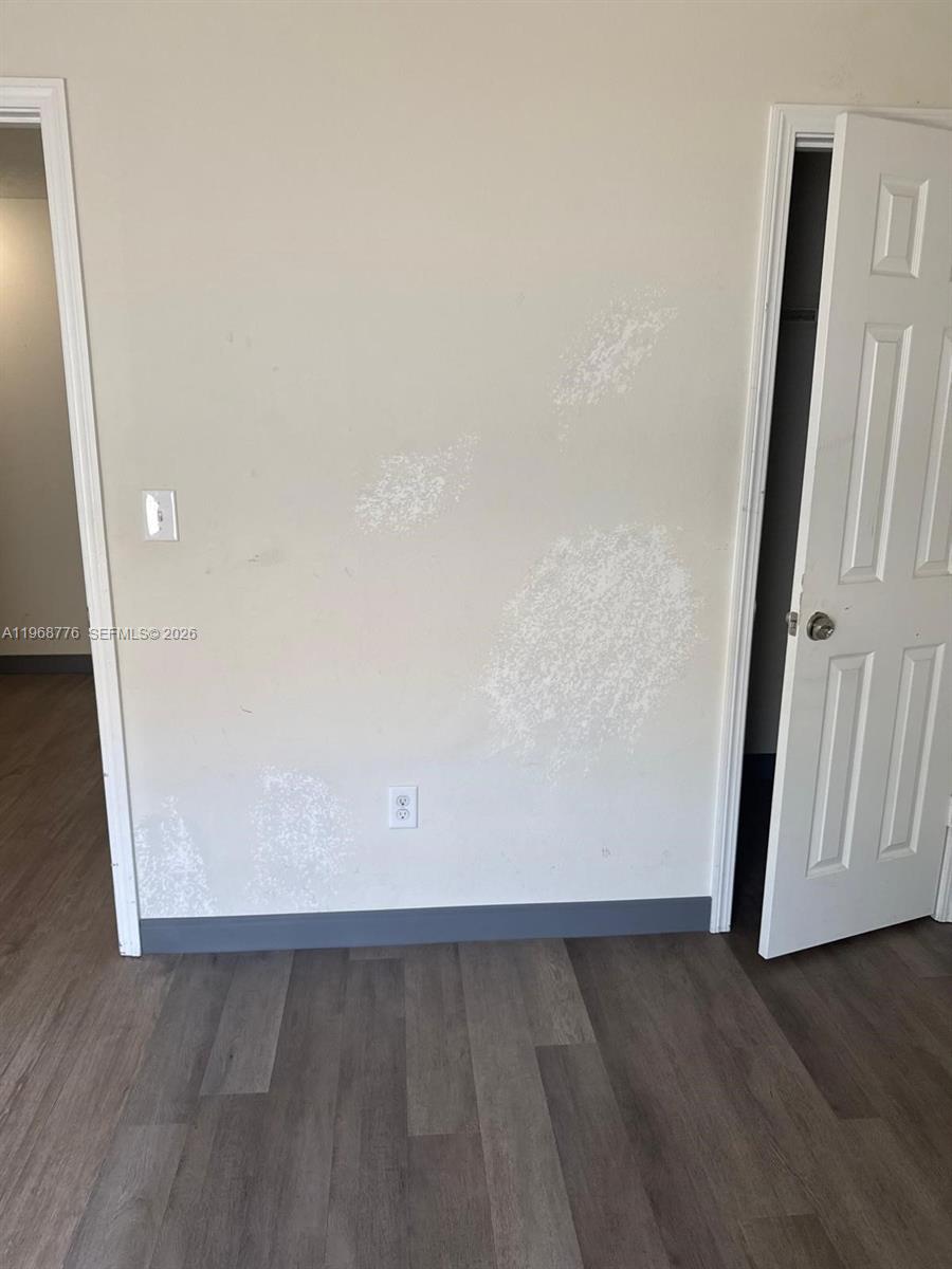 A room with light-colored walls showing patches of paint wear and dark wood-look flooring — 4717 Chatterton Way, Riverview FL 33578, RIVERVIEW, FL