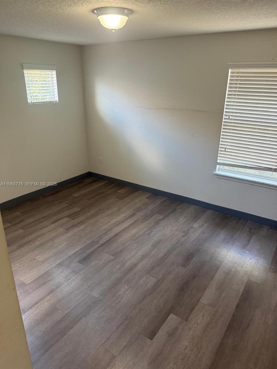 An empty bedroom features light-colored walls, dark baseboards, and wood-look laminate flooring — 4717 Chatterton Way, Riverview FL 33578, RIVERVIEW, FL