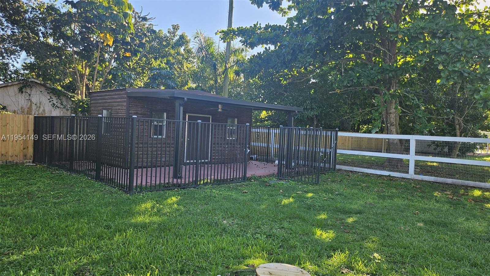 A small wooden shed with a covered patio sits in a fenced backyard — 16400 SW 173rd Ave, Miami FL 33187, MIAMI, FL