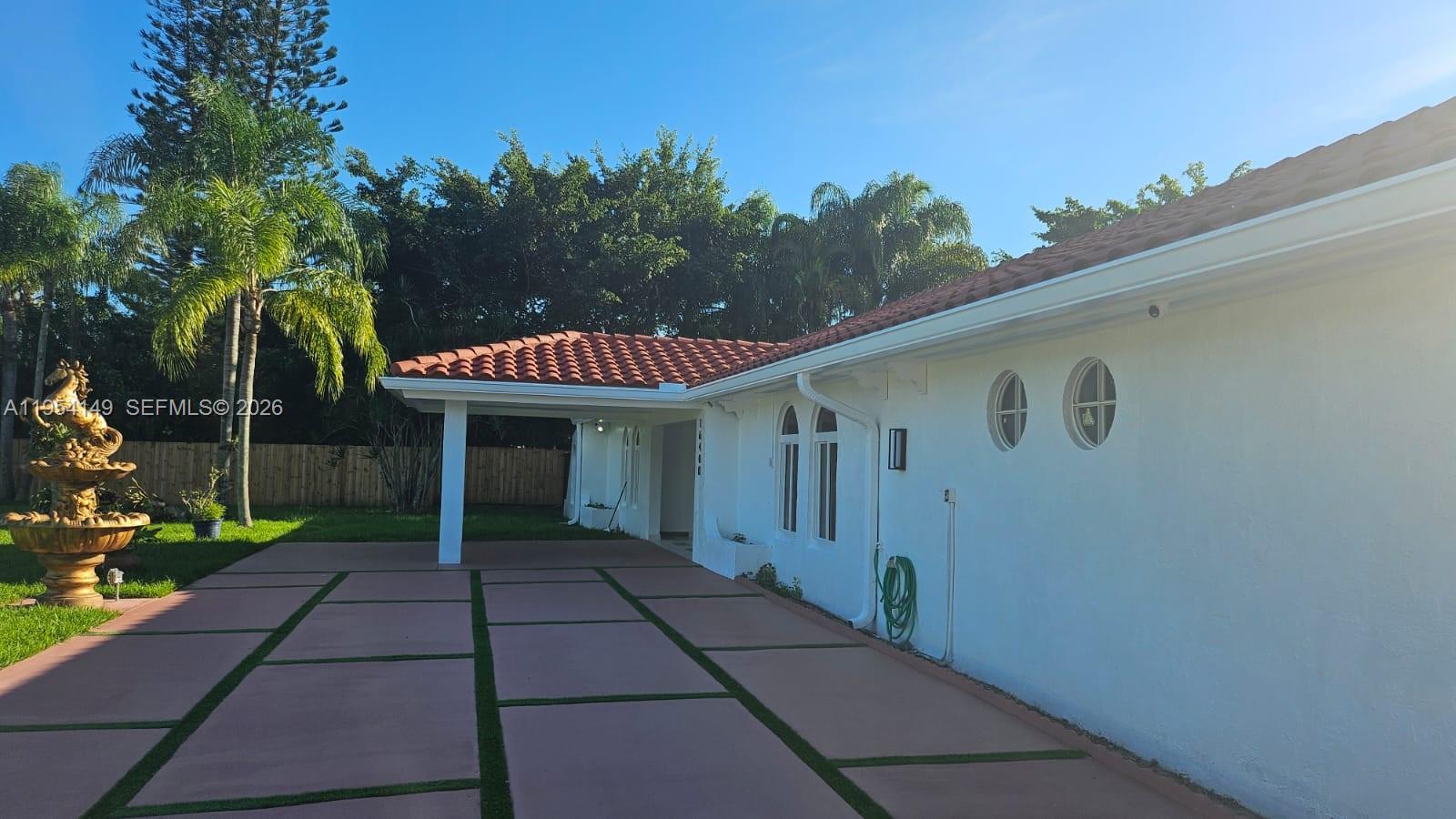 A white house with a red tile roof features a paved driveway and a fountain — 16400 SW 173rd Ave, Miami FL 33187, MIAMI, FL