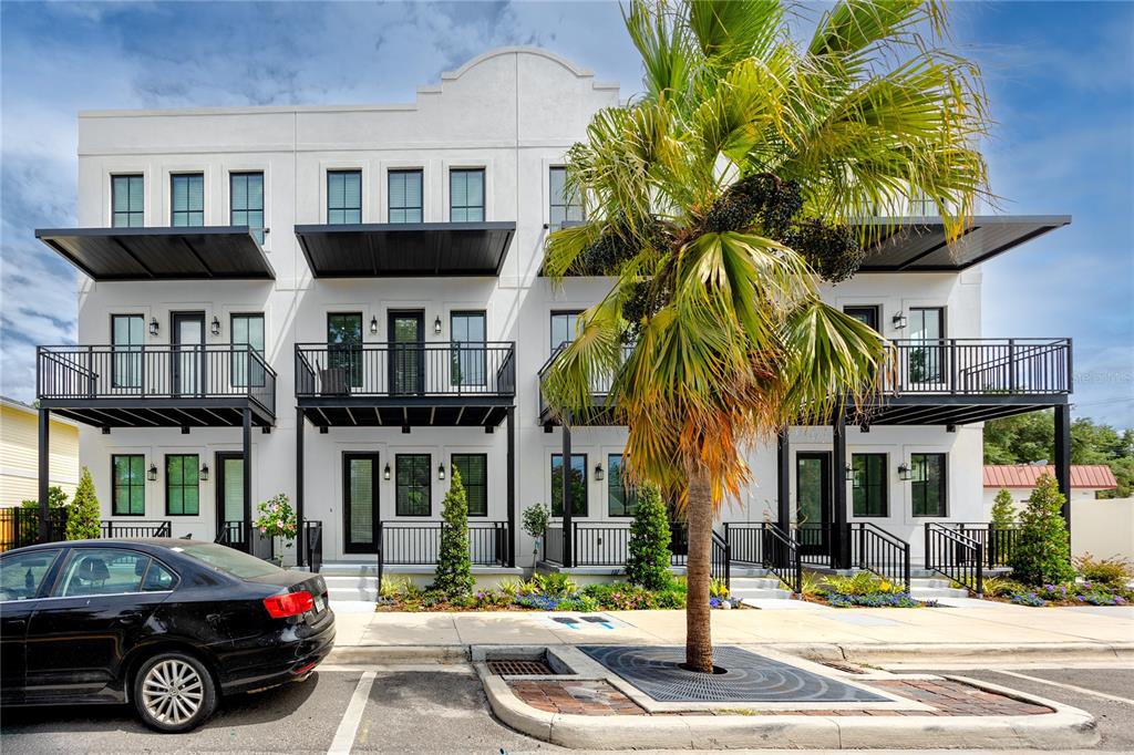 A three-story white townhouse building with black balconies and a palm tree in front — 1308 E COLUMBUS DRIVE UNIT 2, TAMPA, FL