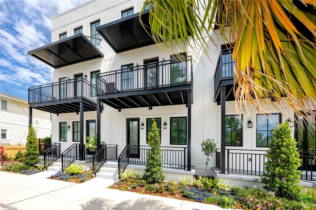 A modern white multi-story townhouse features black metal balconies, railings, and window frames — 1308 E COLUMBUS DRIVE UNIT 2, TAMPA, FL