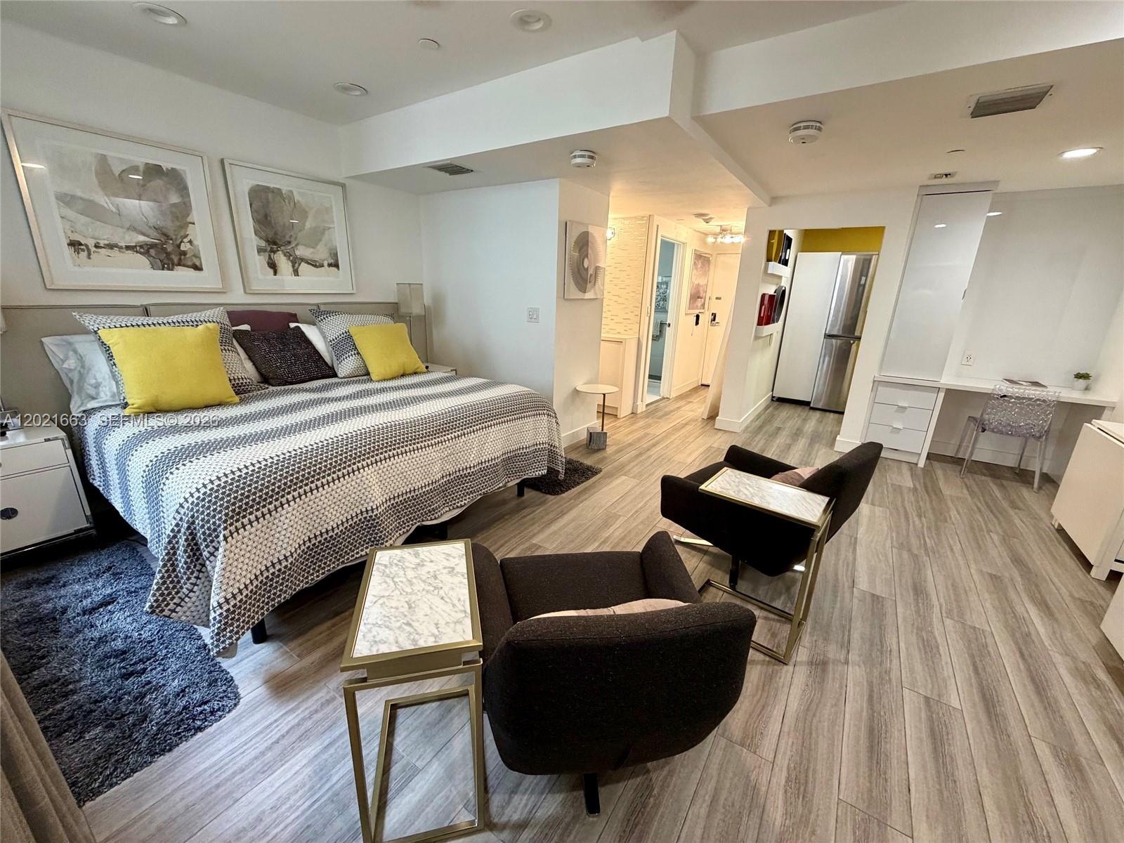 A bedroom features a bed, two armchairs with side tables, and a built-in desk area — AVENTURA, FL