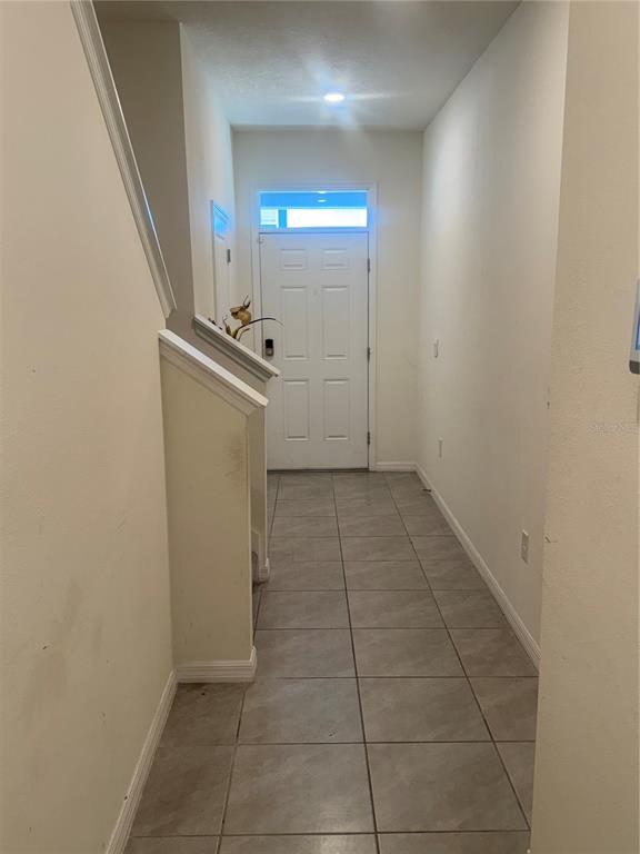A tiled entryway features a white front door and a staircase with a partial wall — 33074 TULIP PETAL LANE, WESLEY CHAPEL, FL