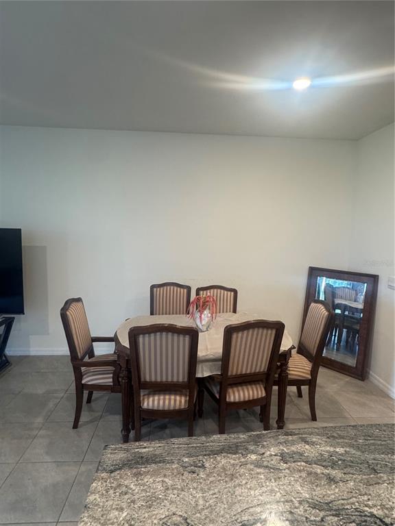 A dining area features a wooden table with six striped chairs and a floor mirror — 33074 TULIP PETAL LANE, WESLEY CHAPEL, FL