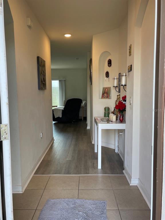 An entryway with tile flooring leads into a hallway with wood-look floors and a console table — 320 LIBERTY BOULEVARD, DAVENPORT, FL