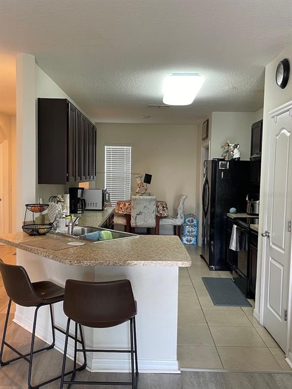 A kitchen features dark cabinets, a speckled countertop, a breakfast bar, and black appliances — 320 LIBERTY BOULEVARD, DAVENPORT, FL