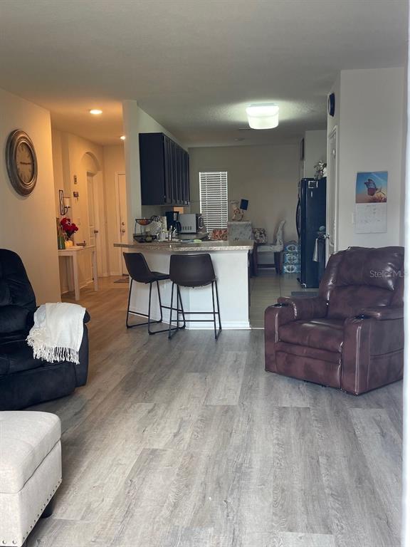 A living room with wood-look flooring leads to a kitchen featuring a breakfast bar — 320 LIBERTY BOULEVARD, DAVENPORT, FL
