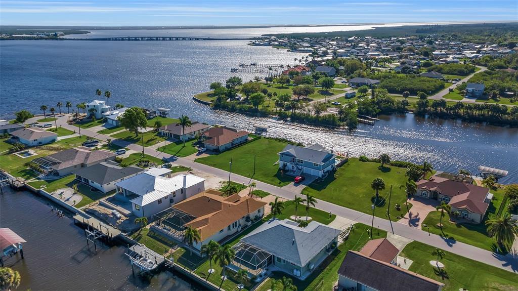 An aerial view shows waterfront houses with boat docks along a canal near a bay — 5142 LATHAM TERRACE, PORT CHARLOTTE, FL