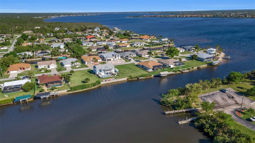 An aerial view shows waterfront houses along a canal leading into a large bay — 5142 LATHAM TERRACE, PORT CHARLOTTE, FL