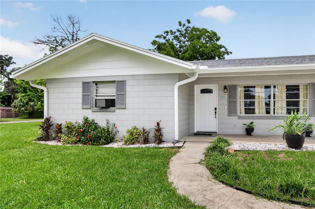 A gray concrete block house with a white front door and a concrete walkway — 555 WINOGENE AVE, UMATILLA, FL