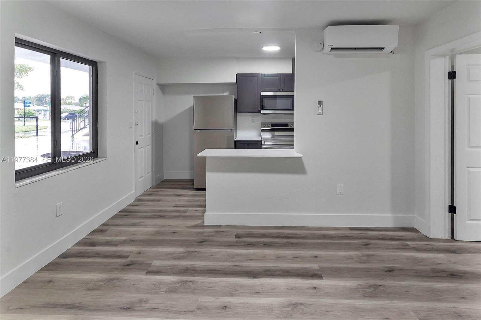This room features light wood-look flooring, a kitchen pass-through, and a wall-mounted air conditioner — 4037 SW 65th Ave # 11, South Miami FL 33155, SOUTH MIAMI, FL