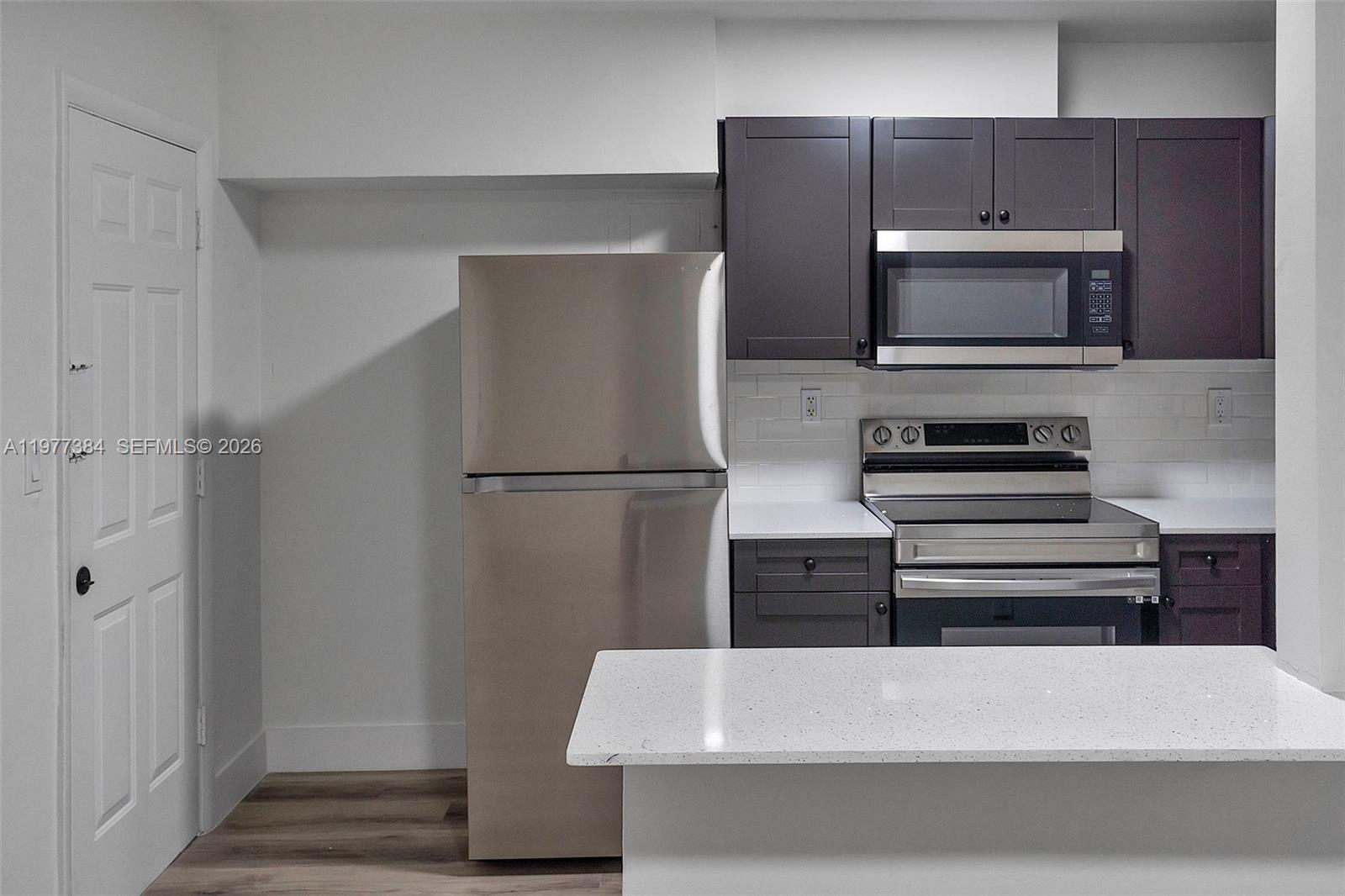 A kitchen features dark gray cabinets, stainless steel appliances, and white quartz countertops — 4037 SW 65th Ave # 11, South Miami FL 33155, SOUTH MIAMI, FL