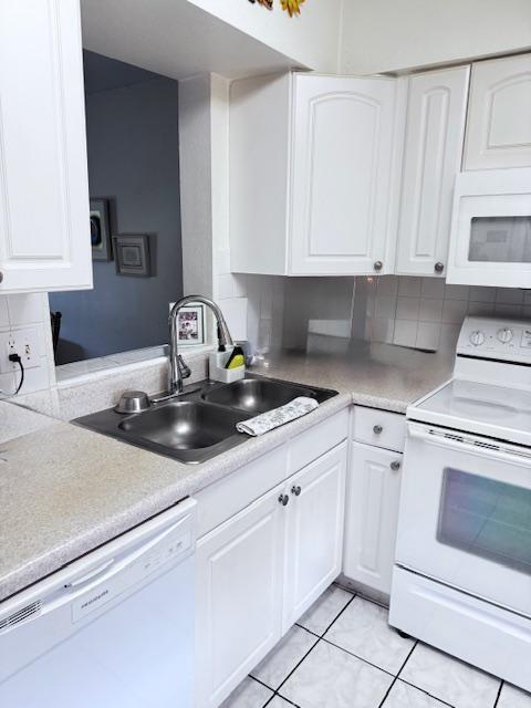 A kitchen features white cabinets, a double-basin sink, and white appliances against a tiled floor — 7320 Lake Circle Drive # 407, Margate FL 33063, MARGATE, FL