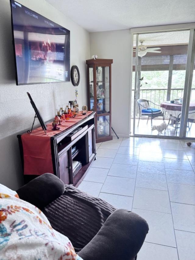 A living room features a television, media console, display cabinet, tile flooring, and a balcony — 7320 Lake Circle Drive # 407, Margate FL 33063, MARGATE, FL