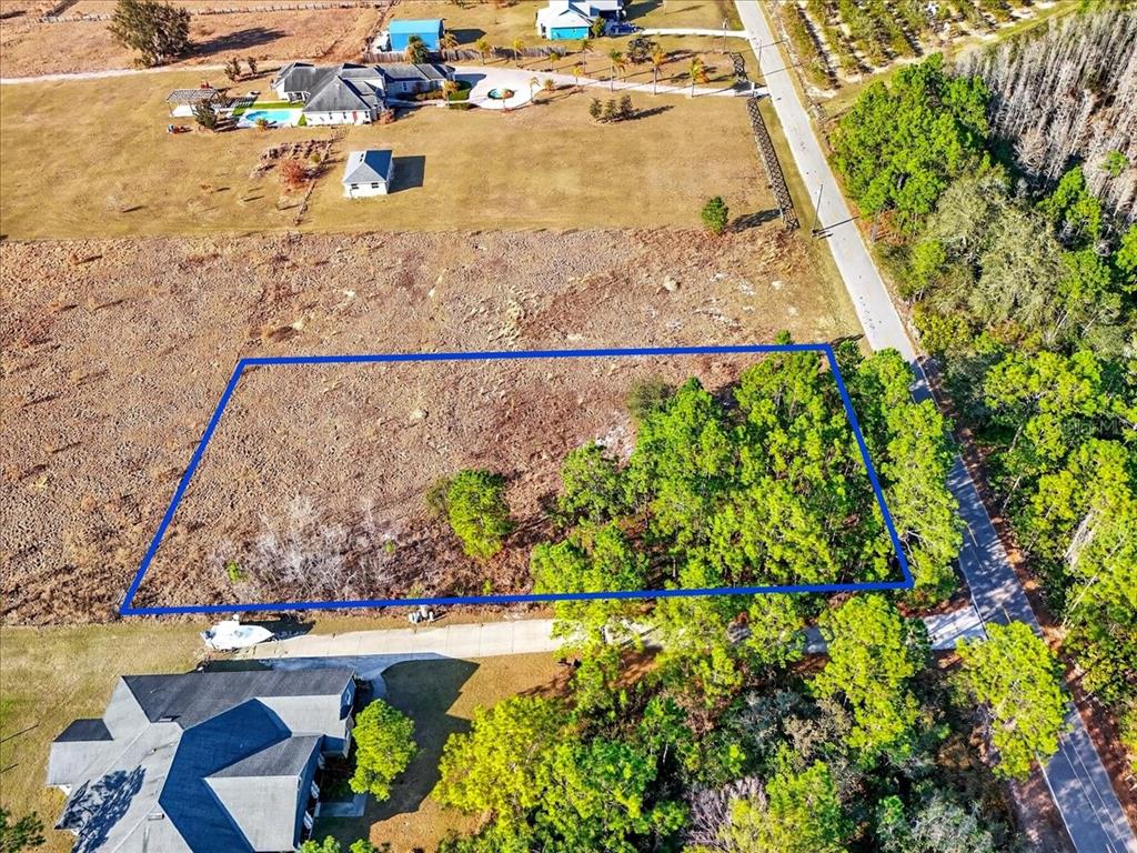 An aerial view shows a rectangular plot of land outlined in blue near a road — SWEET HILL ROAD, POLK CITY, FL
