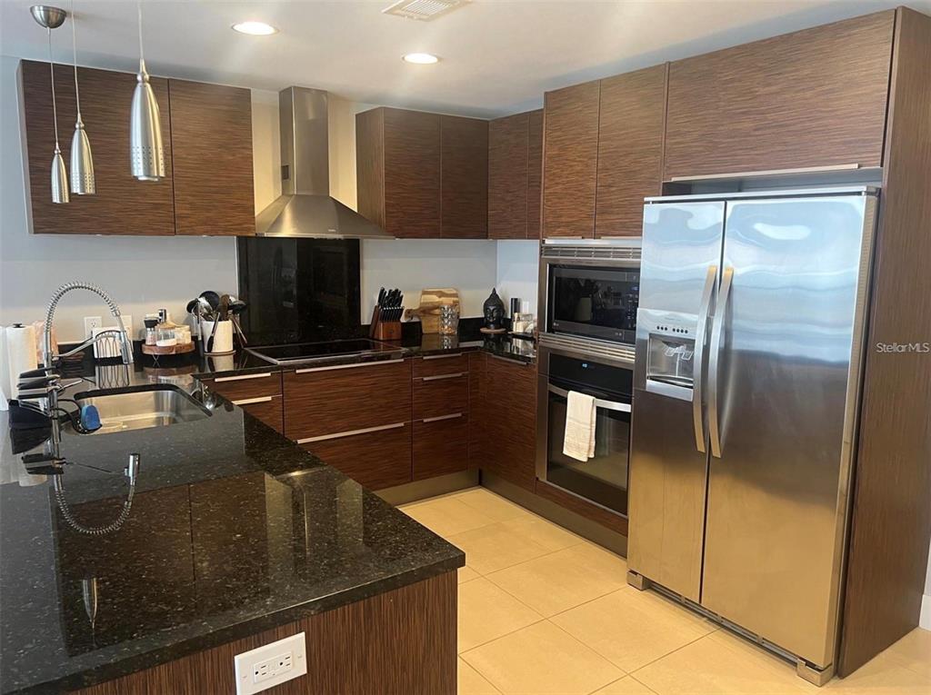 A modern kitchen features dark wood cabinetry, black granite countertops, and stainless steel appliances — 145 2ND AVENUE S UNIT 614, ST PETERSBURG, FL