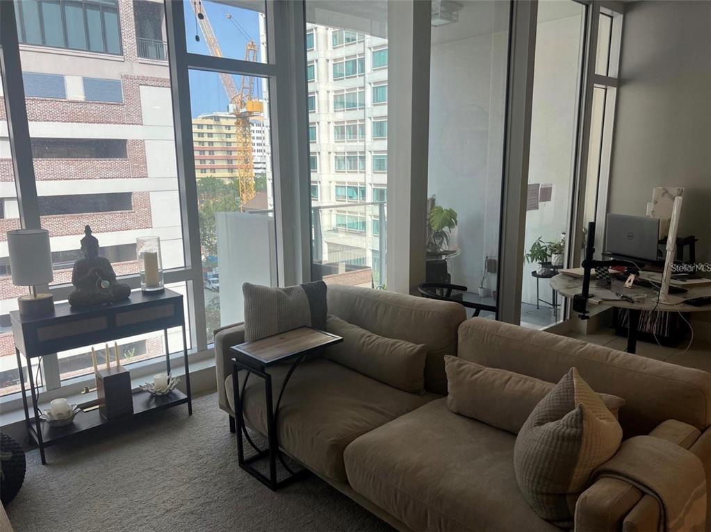 A living room with a beige sofa, a side table, and floor-to-ceiling windows — 145 2ND AVENUE S UNIT 614, ST PETERSBURG, FL