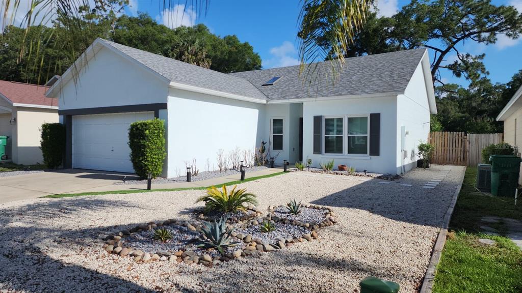 A single-story house with a white exterior, a two-car garage, and a gravel front yard — 327 HERITAGE ESTATES LANE, DELAND, FL
