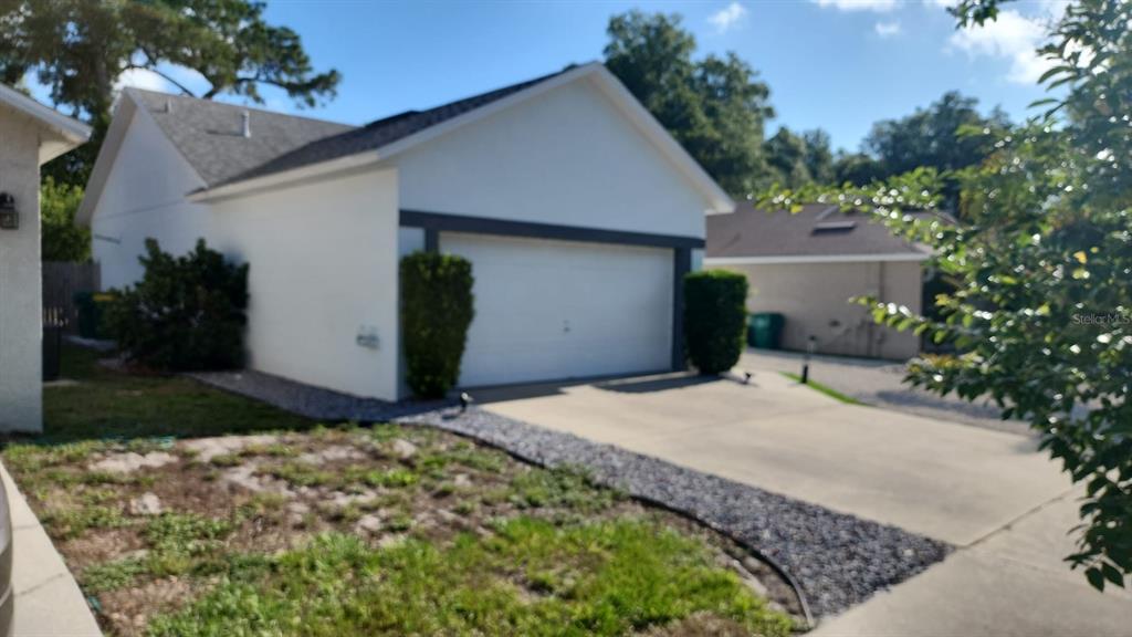 A white house exterior features a two-car garage, a concrete driveway, and landscaped front yard — 327 HERITAGE ESTATES LANE, DELAND, FL