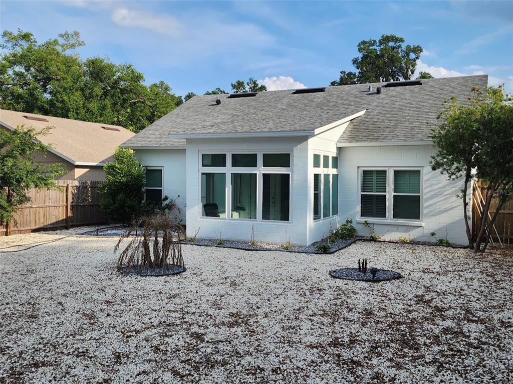 The exterior of a white house with a gravel yard and large windows — 327 HERITAGE ESTATES LANE, DELAND, FL